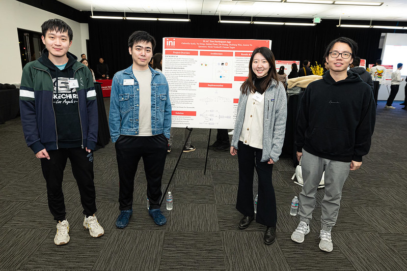 Students stand near their presentation poster